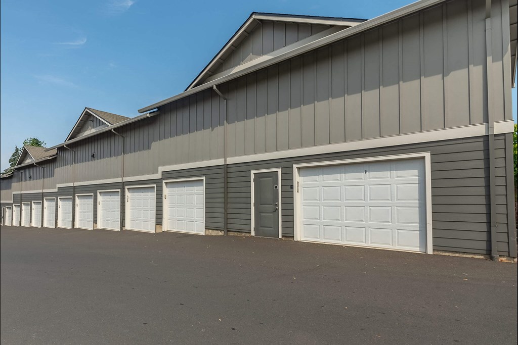 A long building with a grey facade and white garage doors at Sandyplace Apartment Homes, Oregon, 97055