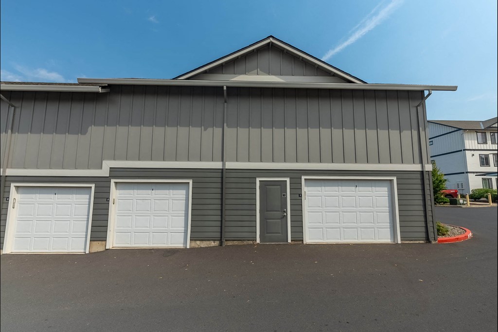 A grey building with three white garage doors at Sandyplace Apartment Homes, Sandy, OR, 97055