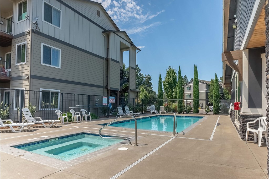 A swimming pool surrounded by lounge chairs and apartment buildings. A swimming pool surrounded by lounge chairs and apartment buildings at Silverplace Apartment Homes, Oregon, 97381
