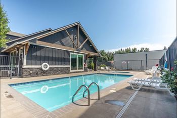 A pool with a slide and a house behind it.