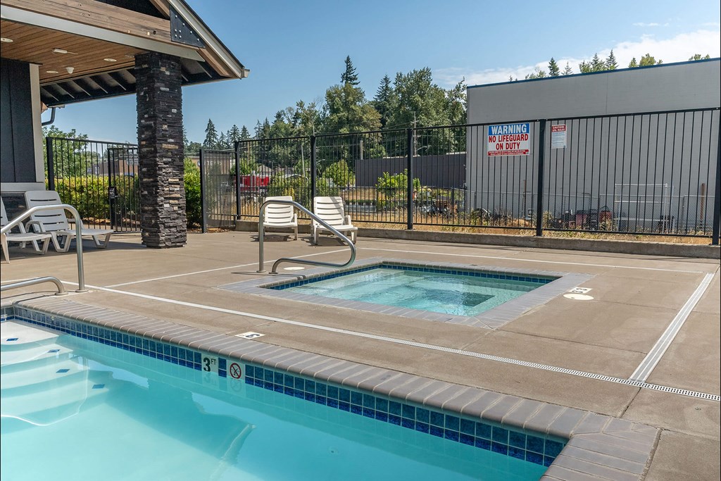 A pool surrounded by a black fence with a warning sign on it at Silverplace Apartment Homes, Silverton, Oregon