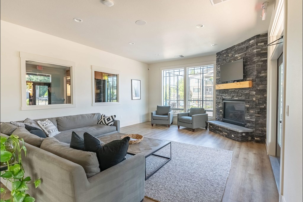 A living room with a grey couch and a stone fireplace at Silverplace Apartment Homes, Silverton, 97381