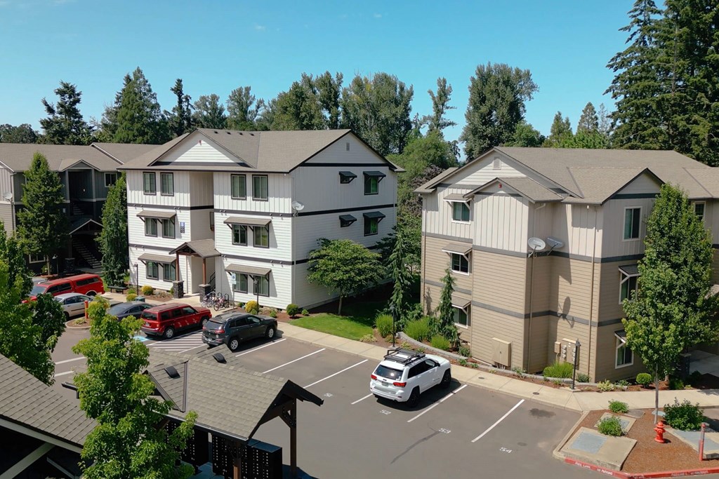 A white and beige apartment complex with a parking lot in front at Silverplace Apartment Homes, Silverton, OR, 97381
