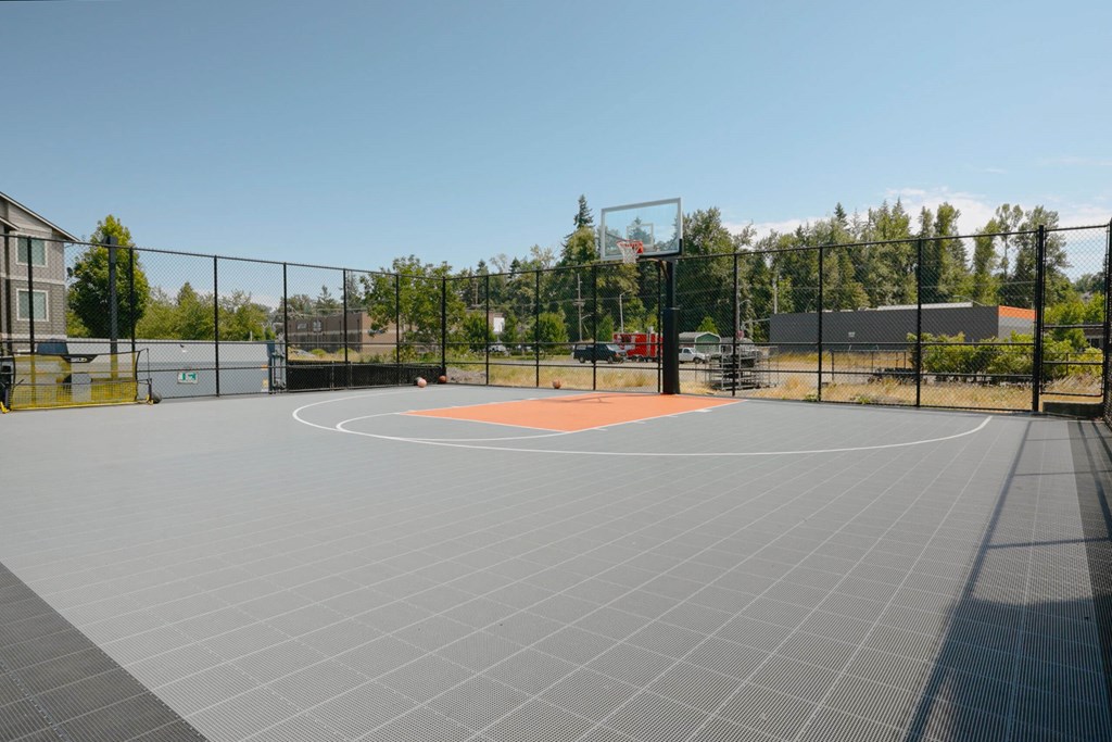 A basketball court is surrounded by a fence and has a net in the middle at Silverplace Apartment Homes, Silverton, Oregon