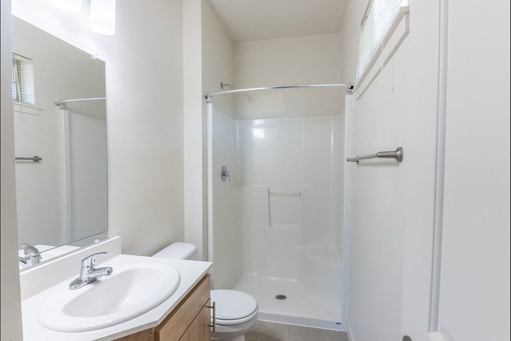 A white bathroom with a toilet, sink, and shower at Silverplace Apartment Homes, Silverton