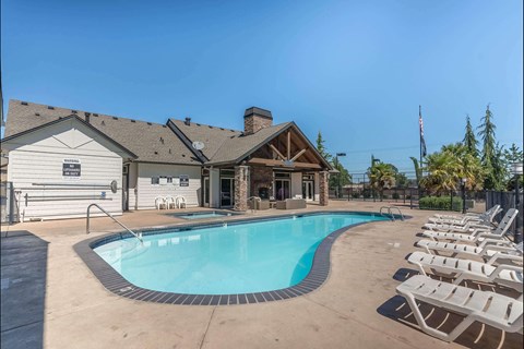 A pool with chairs around it and a building in the background at Stoneplace Apartment Homes, Molalla, OR, 97038