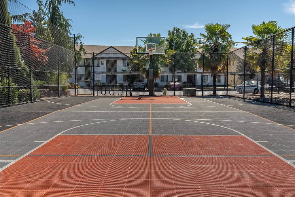 A basketball court with a red surface and a basketball hoop in the middle at Stoneplace Apartment Homes, Molalla, OR