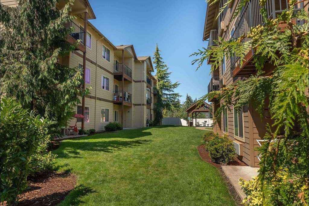 A sunny day at a grassy courtyard surrounded by apartment buildings at Stoneplace Apartment Homes, Oregon