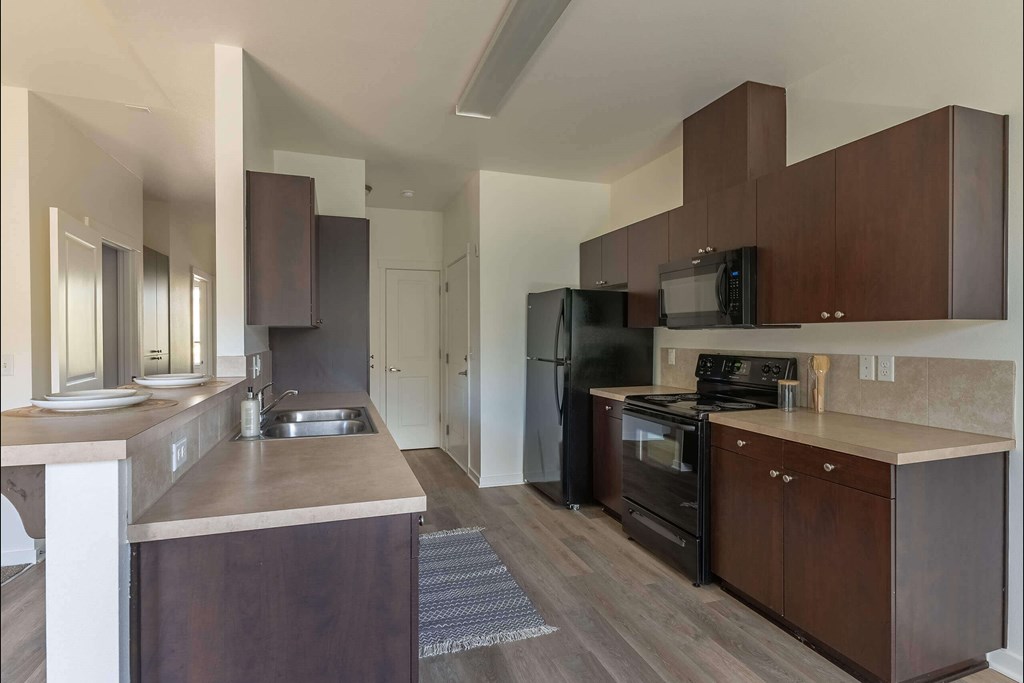 A modern kitchen with dark wood cabinets and appliances at Stoneplace Apartment Homes, Oregon