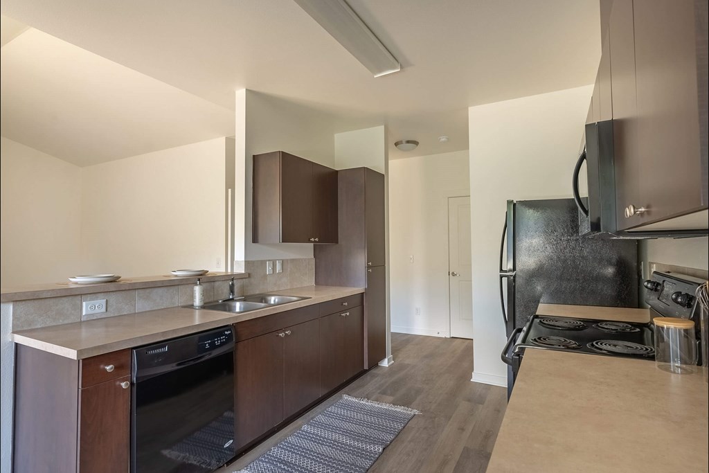 A modern kitchen with dark wood cabinets and stainless steel appliances at Stoneplace Apartment Homes, Oregon