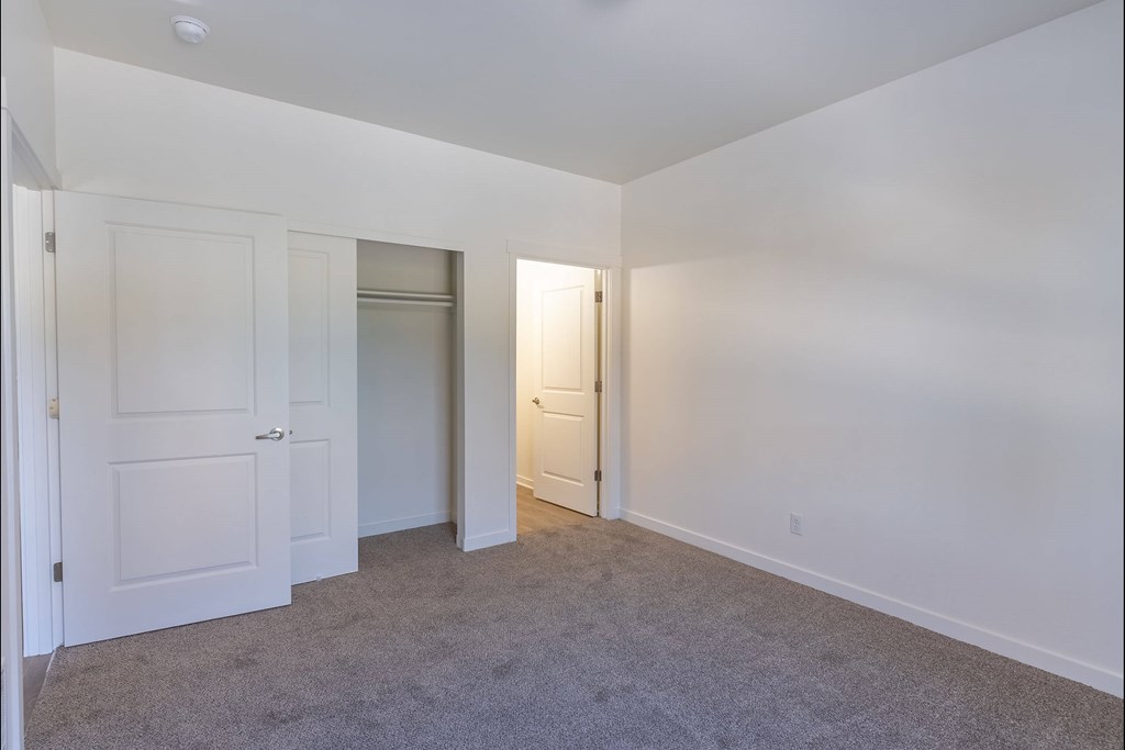 A room with white walls and carpeted floor with two doors at Stoneplace Apartment Homes, Molalla, OR