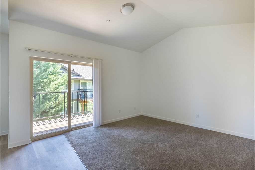 A room with a carpeted floor and a sliding glass door leading to a balcony at Stoneplace Apartment Homes, Molalla