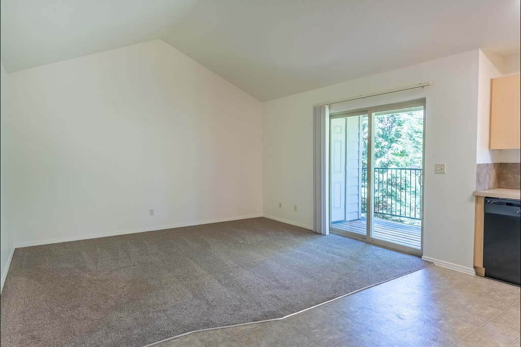 A room with a carpeted floor and a sliding glass door leading to a balcony at Stoneplace Apartment Homes, Molalla, OR