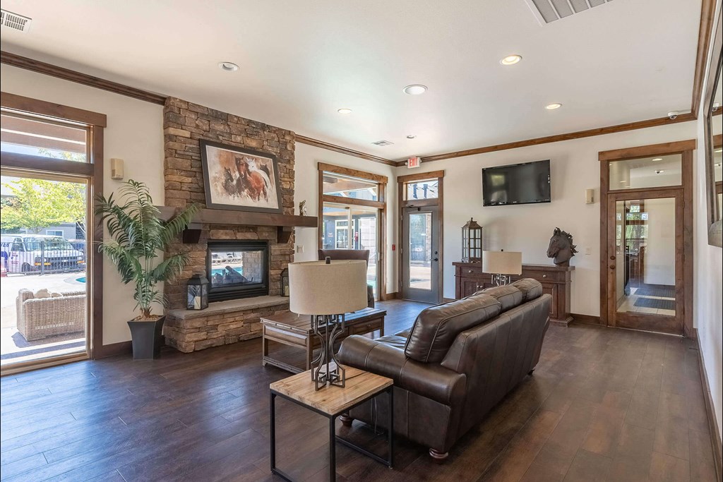 A living room with a stone fireplace and a flat screen TV mounted on the wall at Stoneplace Apartment Homes, Molalla, OR