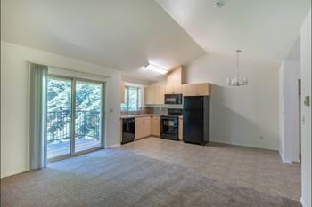 A spacious living room with a kitchen area in the background.