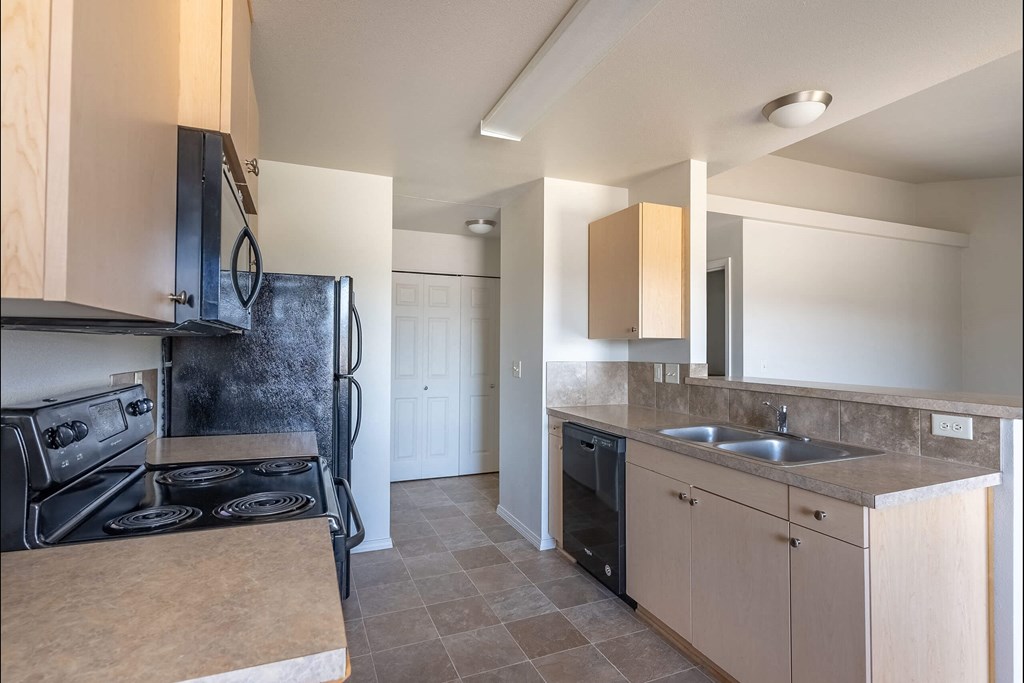 A kitchen with a black stove top oven and a black refrigerator at Stoneplace Apartment Homes, Molalla, 97038