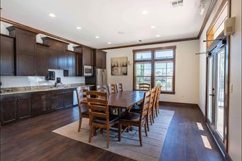 A kitchen with dark wood cabinets and a dining table with chairs.