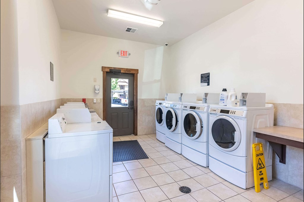 A laundromat with washers and dryers and an exit sign at Stoneplace Apartment Homes, Molalla