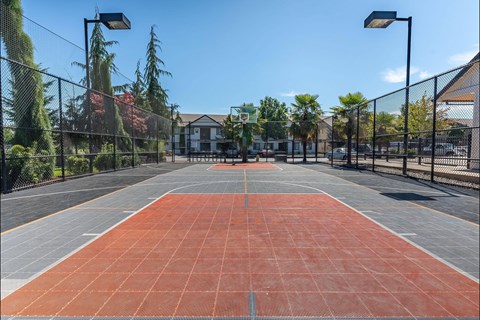 A tennis court with a net and a building in the background at Stoneplace Apartment Homes, Molalla, 97038