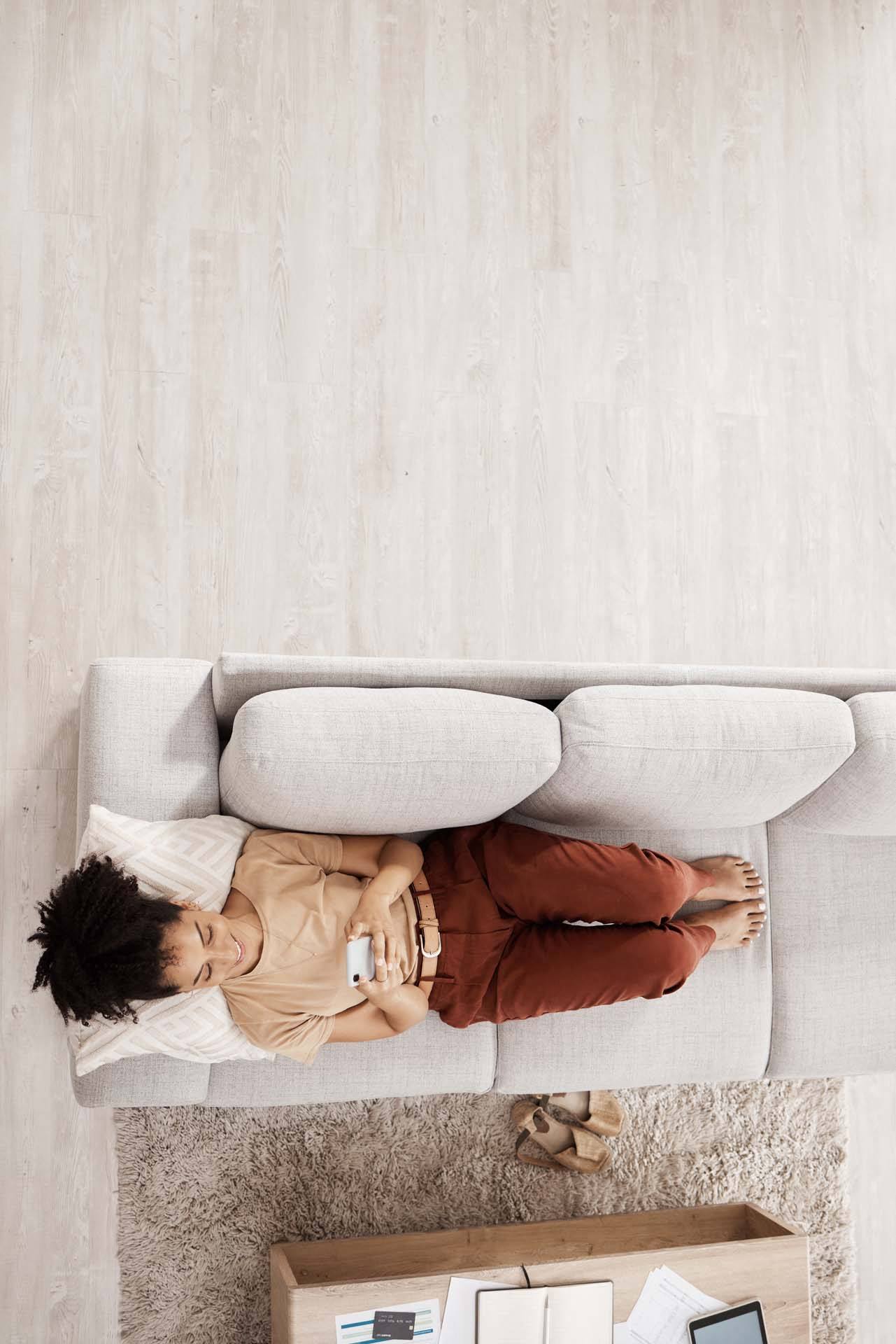 A person is lying on a grey couch with a remote control in hand at The Hub Hermiston Apartments, Hermiston, 97838