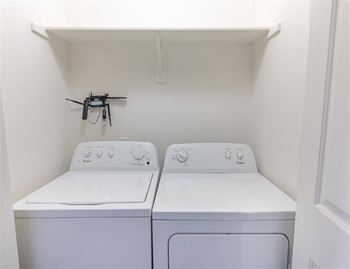 Two white front loading washing machines in a small laundry room.