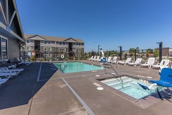 A large outdoor swimming pool with lounge chairs and a building in the background.