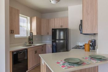 A kitchen with a black fridge and wooden cabinets.