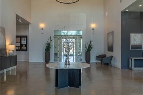 A large, round table sits in the middle of a spacious room with a glass wall behind it.