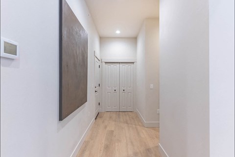 A hallway with a wooden floor and white walls.