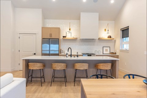 A kitchen with a white counter top and bar stools.