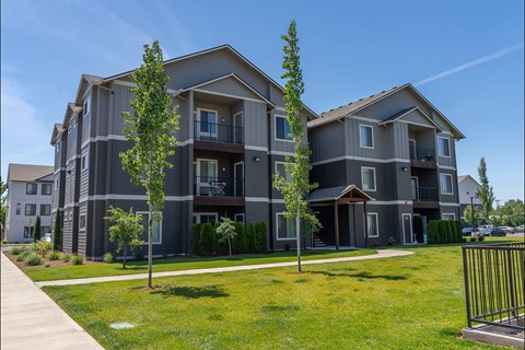 A modern apartment building with a well-maintained lawn in front.