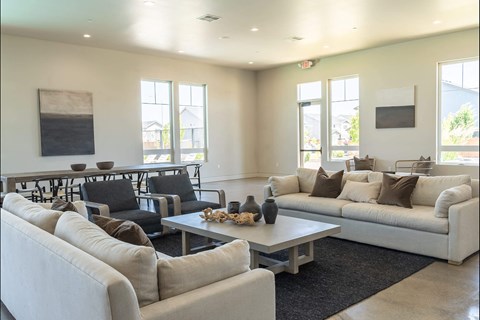 A living room with a white couch, black chairs, and a coffee table.