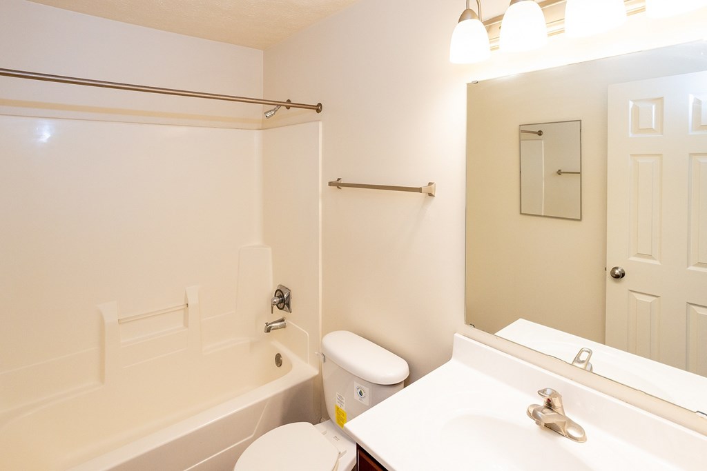 A white bathroom with a toilet, sink, and bathtub.