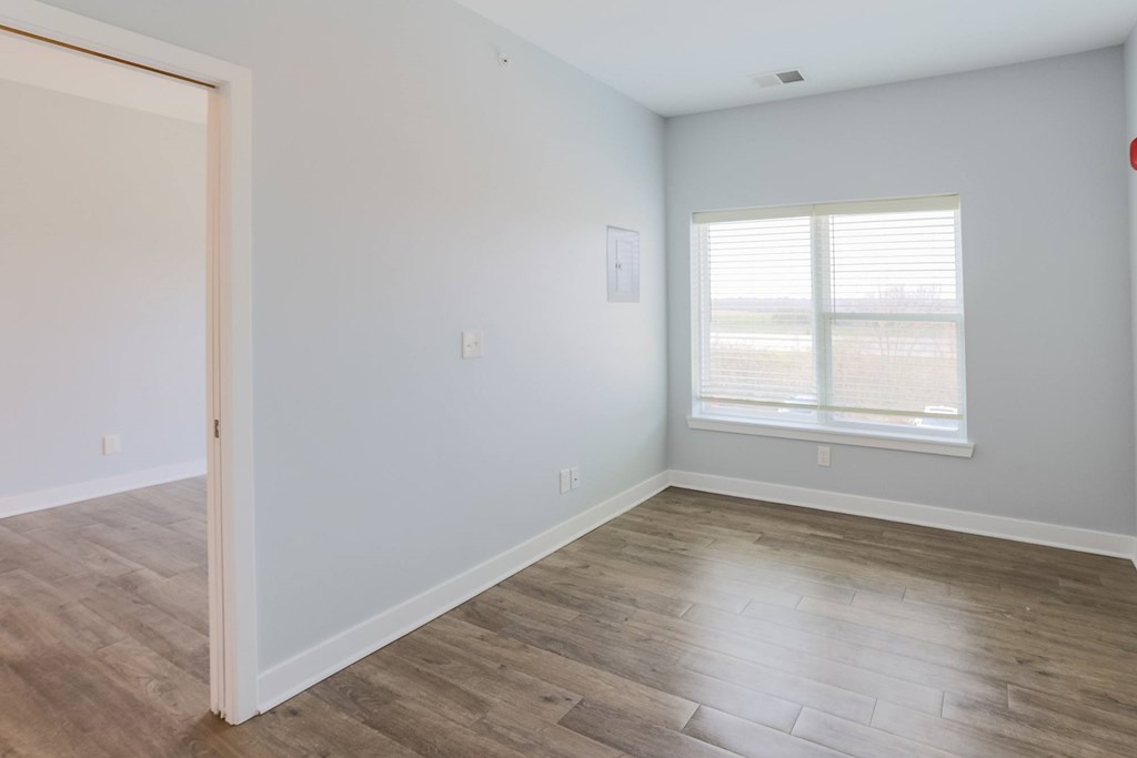 A room with a wooden floor and a window with blinds.
