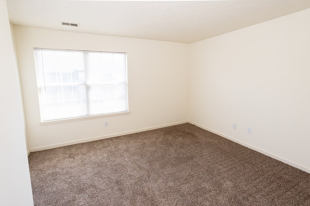 A room with a window and carpeted floor.