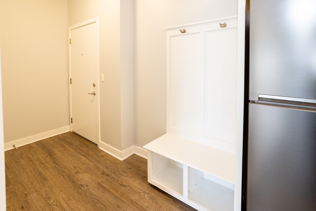 A kitchen with a refrigerator, a door, and a shelf.