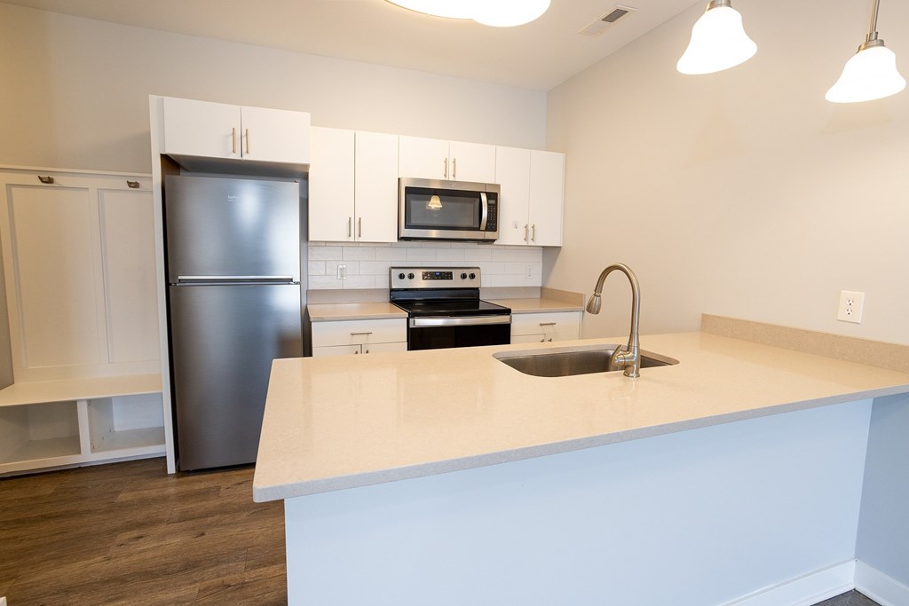A kitchen with a white counter top and a black refrigerator.