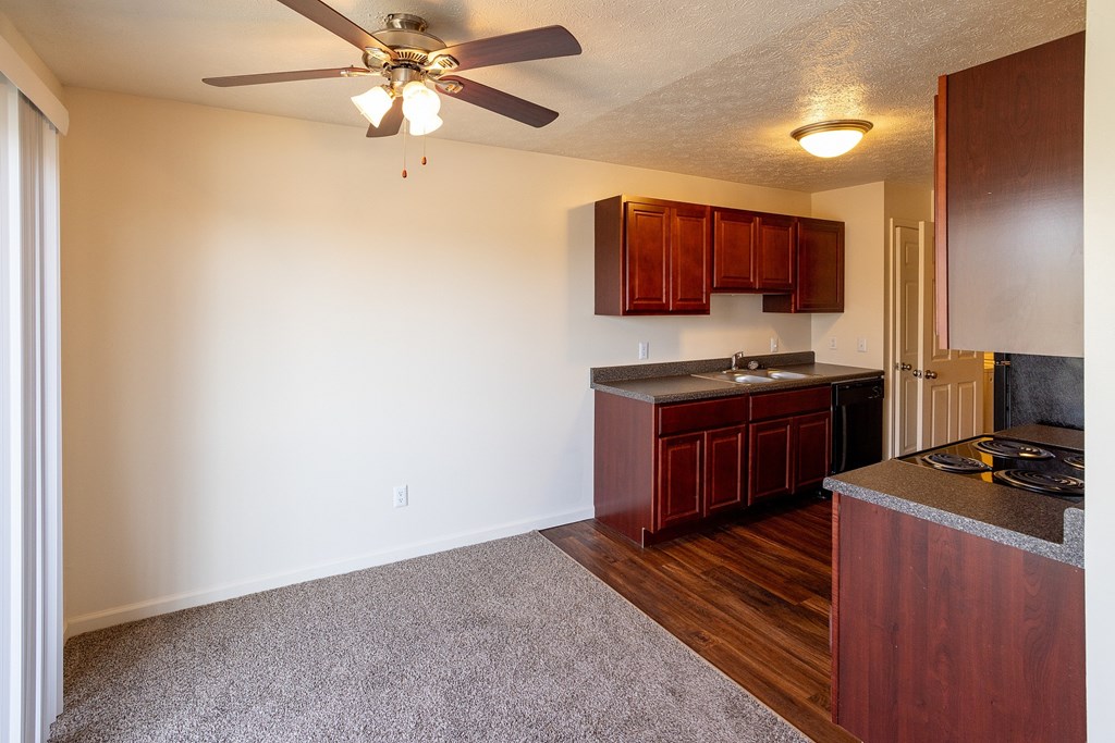 A kitchen with a ceiling fan and wooden cabinets.