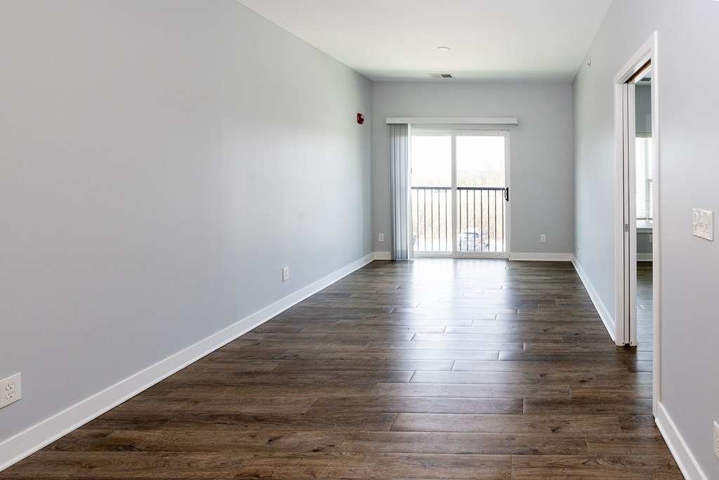 A long, empty room with wooden floors and white walls.
