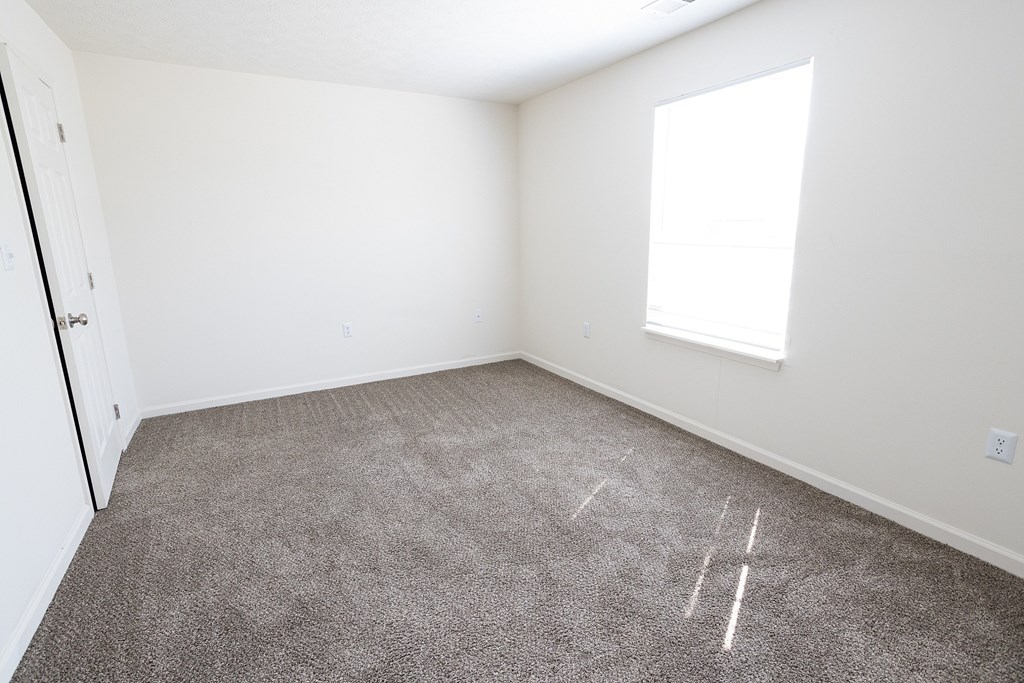 A room with a carpeted floor and a window.