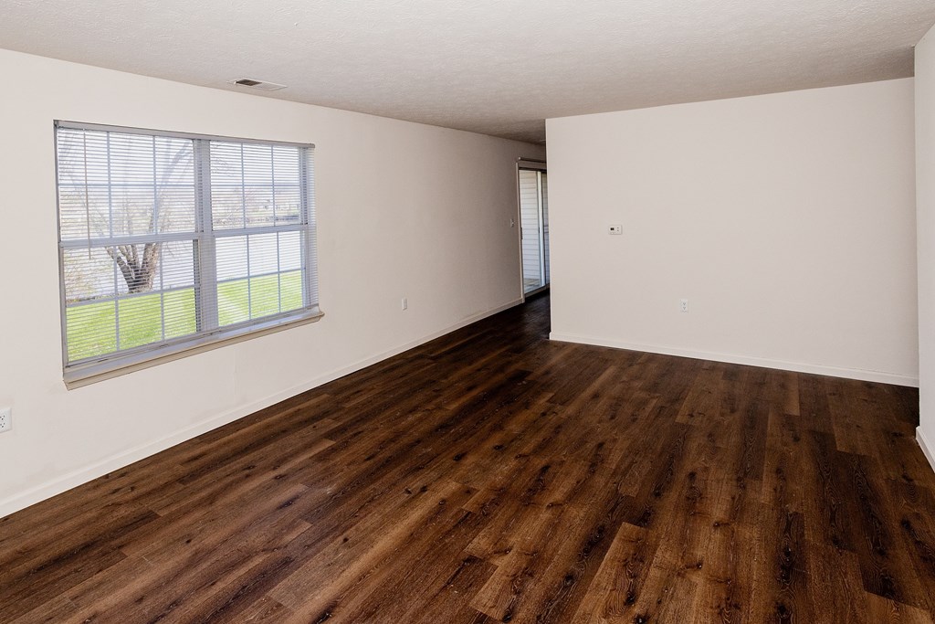 Empty room with wooden flooring and a window.