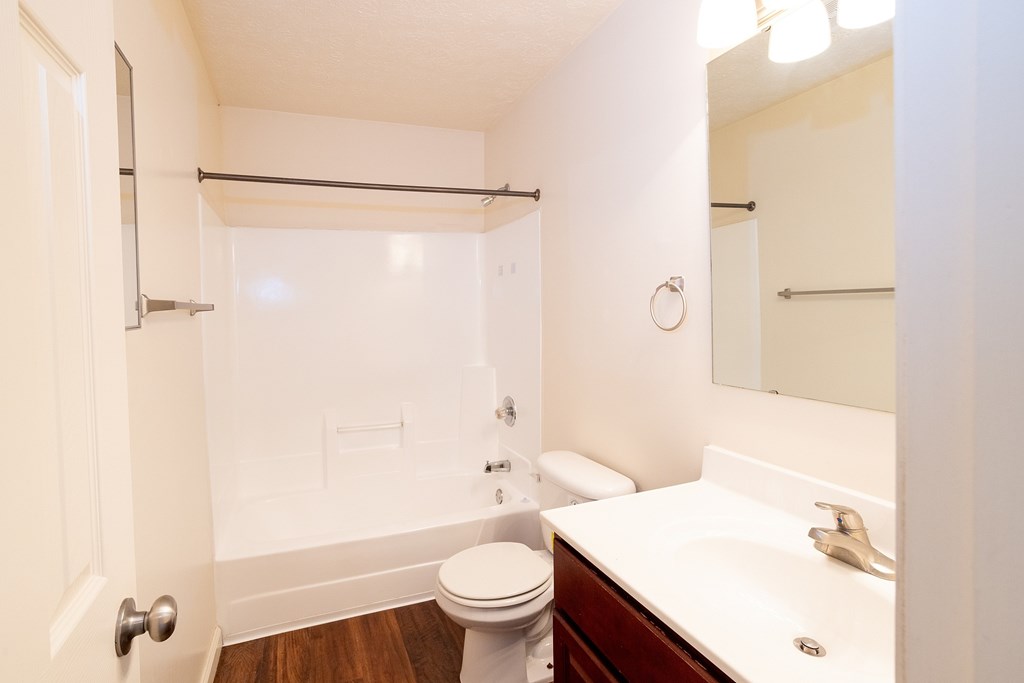 A white toilet is in a small bathroom with a white sink.