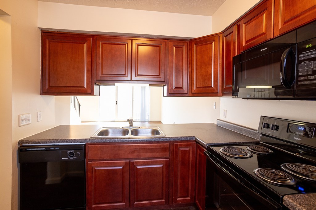 A kitchen with dark wood cabinets and black appliances.