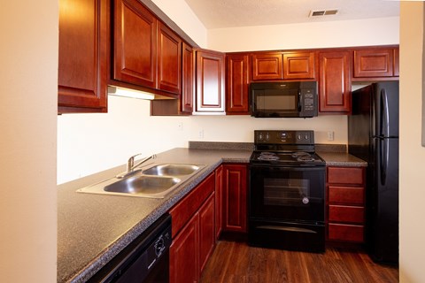 A kitchen with wooden cabinets and black appliances.