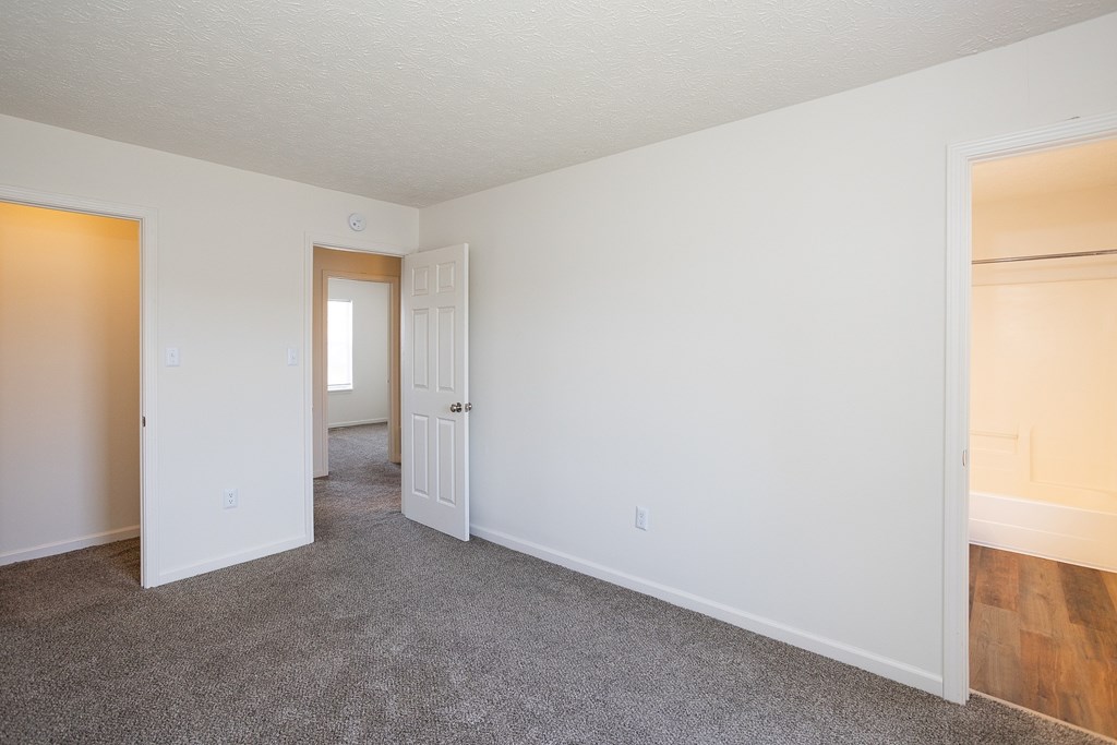 A room with white walls and a grey carpet.
