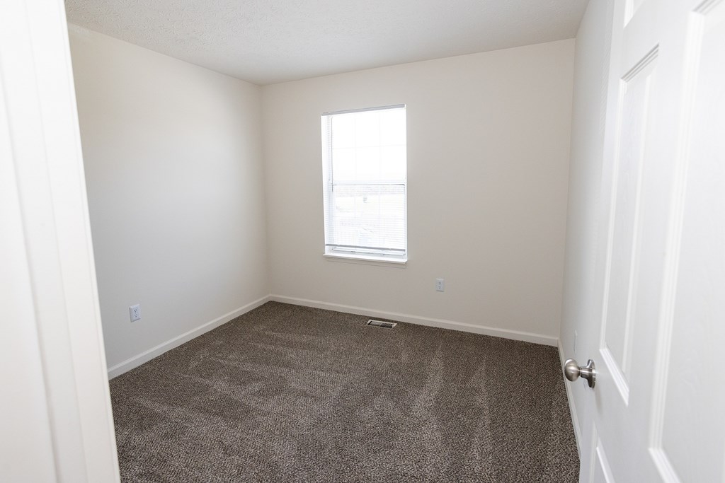 A room with a carpeted floor and a window.