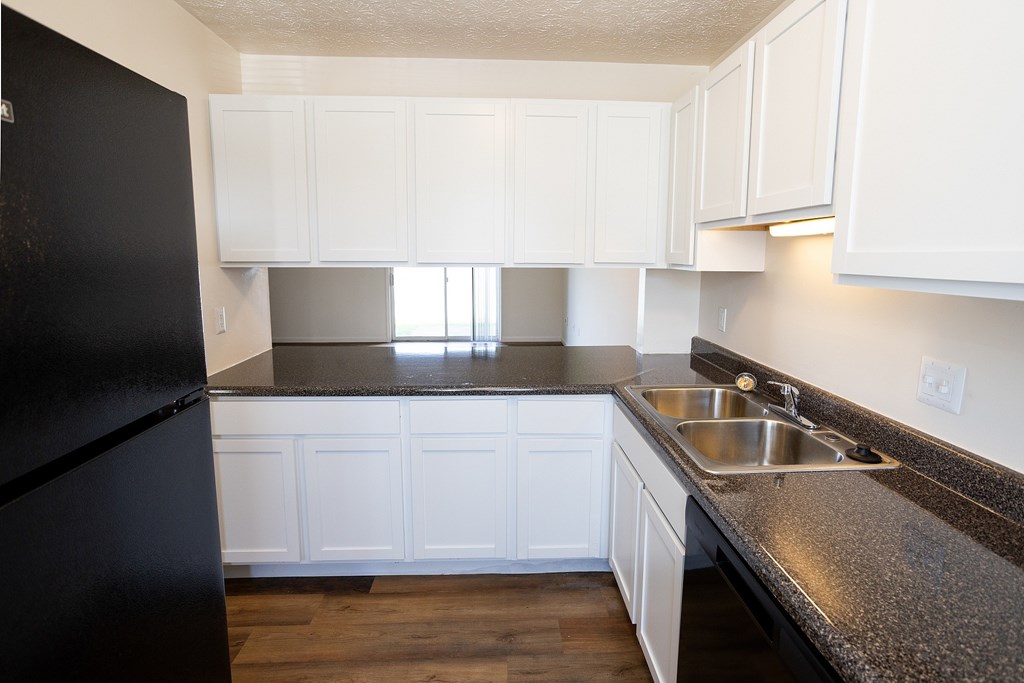 A kitchen with black fridge and white cabinets.