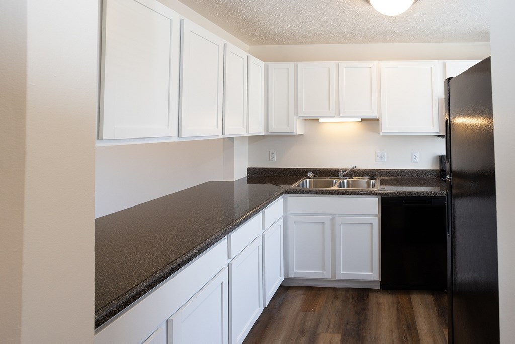 A kitchen with white cabinets and a black refrigerator.