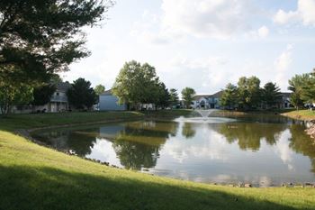 A fountain in the middle of a lake surrounded by trees.