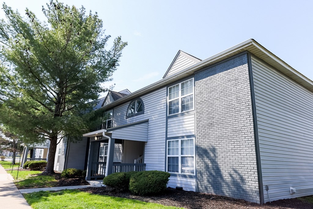 A grey house with a tree in front.
